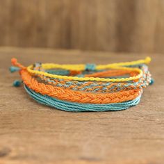 three different colored bracelets sitting on top of a wooden table