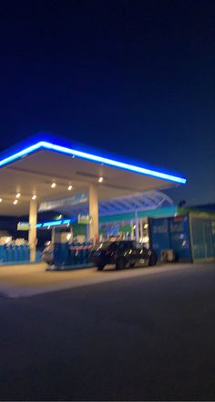 a gas station at night with cars parked in the lot