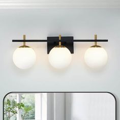 three light bathroom fixture in black and gold with white glass globes on the wall