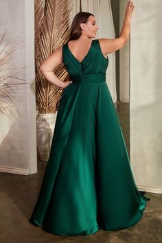 a woman in a long green dress is posing for the camera with her hand on her hip