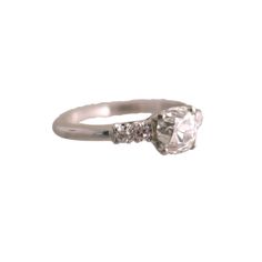 a white gold ring with an oval cut diamond and three small diamonds on the side