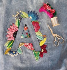 the letters are made out of fabric and flowers, along with some sewing supplies such as scissors