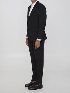 This two-piece suit is made of black virgin wool and includes a single-breasted jacket with peaked lapels, a brooch on the lapel, a front button closure, two front welt pockets, a welt pocket on the chest, and buttoned cuffs. The straight-leg trousers feature a zip, button, and hook-and-eye closure, as well as two side welt pockets and two rear buttoned welt pockets. Size nationality: Italy Buttoned cuffs Peaked lapels Button closure Front pockets Straight leg pants Rear pockets Regular fit Prod Tuxedo Style Pantsuit With Suit Collar For Semi-formal, Semi-formal Tuxedo Pantsuit With Notch Lapel, Evening Pantsuit With Notch Lapel And Pressed Crease, Formal Tuxedo Pantsuit With Lapel Collar, Semi-formal Tuxedo Pantsuit With Lapel Collar, Tailored Elegant Formal Pantsuit, Elegant Tailored Pantsuit For Formal Occasions, Tailored Elegant Pantsuit For Formal Occasions, Formal Tuxedo Suit