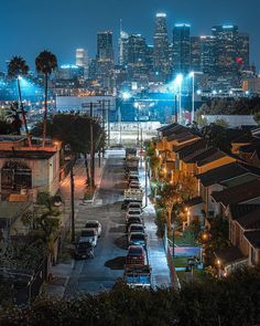 the city skyline is lit up at night, with cars parked on the street below