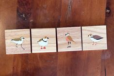 three birds are painted on wooden blocks sitting on a table next to some wood planks