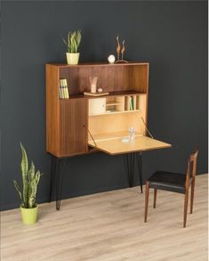 a wooden desk and chair in front of a wall mounted shelf with plants on it