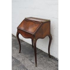 a small wooden table sitting on top of a sidewalk next to a white brick wall