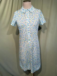 This is a cute vintage dress from the 60's. No labels or tags. It is home sewn.  There isn't a size tag. The bust measures 36", waist 32", see measurements below.  Made of white, blue, green & yellow cotton blend fabric in a small floral print.  The dress is not lined.  It has short sleeves. The collar is small. Buttons down the front to below the waist. The shape is very straight.  The dress is in very good condition, no wear or tear.  No soil or stains.  Measurements were taken with the garment lying flat. If you have never worn vintage before, please measure yourself!! Vintage sizes run smaller than today's sizes, you need to know your measurements! If you have any questions about measuring, please ask before purchasing.  Bust measured 2" below underarm from side seam to side seam: 18" Fitted Retro Vintage Dress With Button Closure, Blue Vintage Dress With Buttons For Vintage Fashion, Blue Vintage Dress With Buttons, Retro Blue Button-up Dress, Retro Vintage Dress With Button Closure, Retro Blue Knee-length Vintage Dress, Vintage Blue Button-up Dress, Fitted Retro Button-up Vintage Dress, Retro Fitted Button-up Vintage Dress