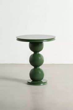 a small green table with three balls on the top and one ball at the bottom