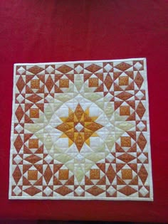 an orange and white quilt on a red surface