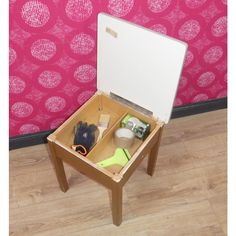 an open suitcase sitting on top of a wooden table in front of a pink wall