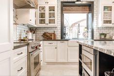 a kitchen with white cabinets and marble counter tops, along with an open window to the outside