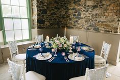 the table is set with blue linens and white chairs