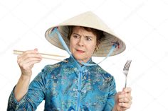 an older woman wearing a hat and holding chopsticks in one hand and fork in the other