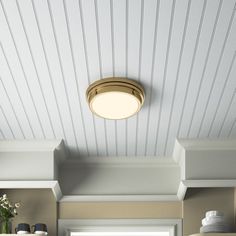 a kitchen with white cabinets and wood paneling on the ceiling is lit by a round light fixture