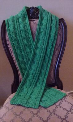 a green knitted scarf sitting on top of a chair