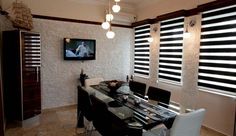 a dining room table and chairs in front of a tv mounted on the wall above it