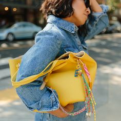 a woman carrying a yellow purse on her shoulder