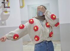 a woman taking a selfie in front of a mirror wearing a sweater with flowers on it