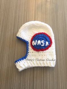 a crocheted hat with the word msh on it sitting on a wooden surface