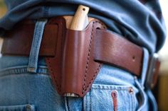 a person wearing jeans with a leather belt around their waist holding a knife in his pocket