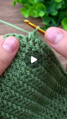 someone is crocheting the stitchs on their green knitted bag with a needle