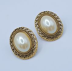 Gorgeous Victorian-style oval pierced earrings by 1928 Jewelry Company. These earrings are framed in beautiful antique gold tone filigree and decorated with pearl cabochons. They are marked with the company's signature pattern on the back. In most cases, the company labeled its products this way. They are high-end stud earrings. It will be a great addition to your vintage jewelry collection. Don't miss out on these gorgeous earrings! 🔹 Condition - the earrings are in good pre-owned condition. All photos are taken in macro mode. Please look carefully at all the photos as they are part of the description to be in agreement with our offer. 🔹 Measure- 1'' x 7/8''. 🔹 Date: Approximately 90th. 🔹 Occasion- wedding, birthday, anniversary, party, or gift-giving for your special loved one. All j Gold Oval Earrings With Intricate Design, Classic Metal Clip-on Earrings For Wedding, Oval Filigree Earrings For Wedding, Oval Wedding Earrings With Intricate Design, Vintage Oval Pierced Earrings, Classic Clip-on Earrings For Vintage Events, Formal Gold Oval Clip-on Earrings, Gold Oval Clip-on Earrings For Formal Occasions, Oval Metal Earrings For Wedding