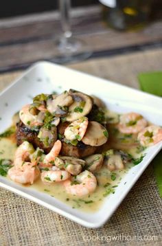 a white plate topped with shrimp and mushrooms