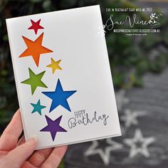 someone holding up a birthday card with colorful stars on the front and back of it