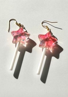 this is a pair of hanging lollipop earrings made to look like stars! the lollipops contain glitter with a mix of pink and white coloring. Best Friend Earrings, Pink Accessories Aesthetic, Star Lollipops, Lollipop Earrings, Cool Earrings, Weird Jewelry, Pretty Jewelry Necklaces, Glitter Art, Funky Earrings