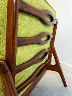 an upholstered green chair with wooden handles