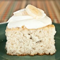 a piece of cake with white frosting and a banana on top is sitting on a green plate