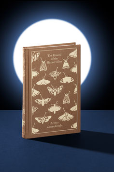 a book sitting on top of a table next to a moon filled sky with moths