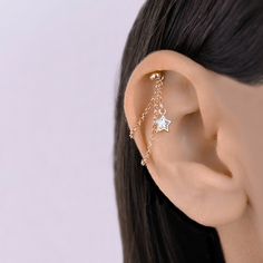 a close up of a person's ear with a star and chain attached to it