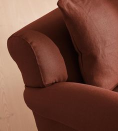 a brown couch with two pillows on it's back and one arm facing the camera