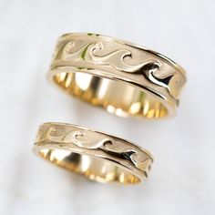 two gold wedding rings sitting next to each other