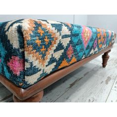 a bench with a colorful rug on top of it and wooden legs in the background