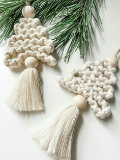 two crocheted ornaments hanging from a pine tree with white yarn and tassels