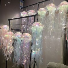 some jellyfish are hanging from a rack in front of a mirror with lights on it