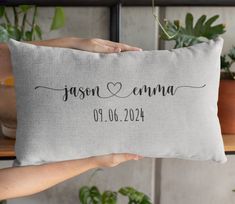 a person holding up a pillow that says,'personalized with the names and date