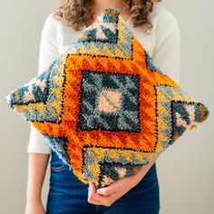 a woman holding a decorative pillow in her hands