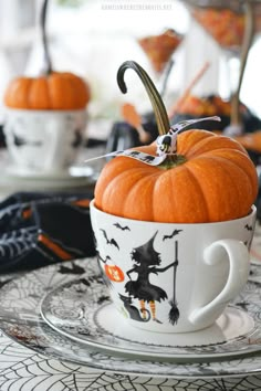 an orange pumpkin sitting in a cup on top of a plate