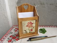 a pen and paper holder sitting on top of a table next to a flowered cloth