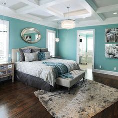 a bedroom with teal walls and white bedding in the center, along with a mirror on the wall