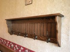 a wooden shelf with five hooks on it and a bench in front of the wall