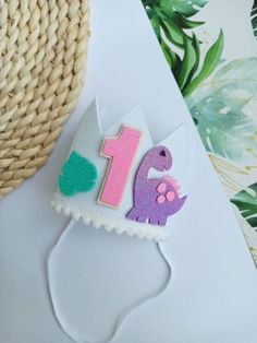 a birthday cake shaped like a dinosaur on top of a white table next to a straw hat