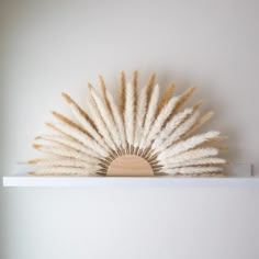 a white shelf topped with lots of dry grass and a wooden object on top of it