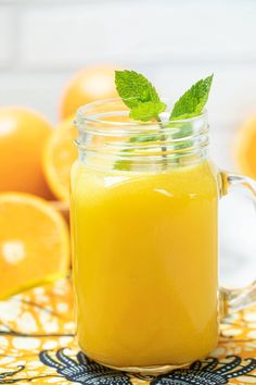 a mason jar filled with orange juice and garnished with a green leaf on top