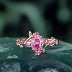 a pink ring sitting on top of a green leafy plant with leaves around it