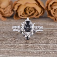 a black and white diamond ring sitting on top of a wooden table next to roses